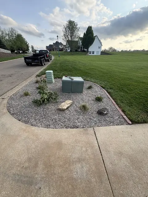 Completed corner bed with decorative rock, shrubs, and edging