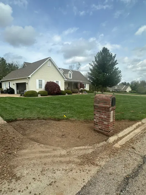 Mailbox bed during installation, with exposed soil around the brick mailbox