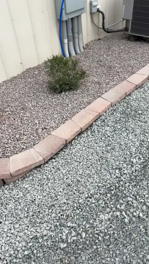 Completed block edging and rock bed beside a building